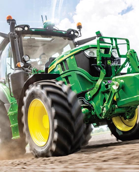 John Deere 6R-tractor met frontladerconsoles rijdt over een akker